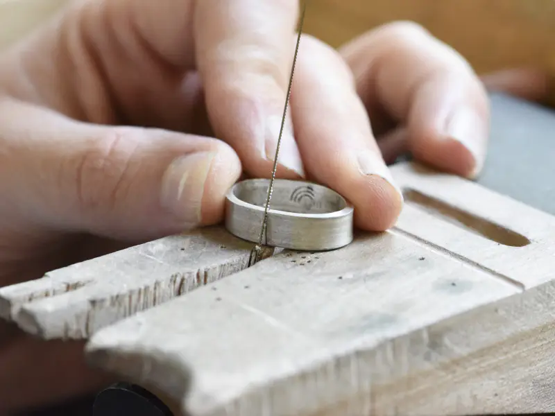 Piercing a wide silver band with a jeweler's saw